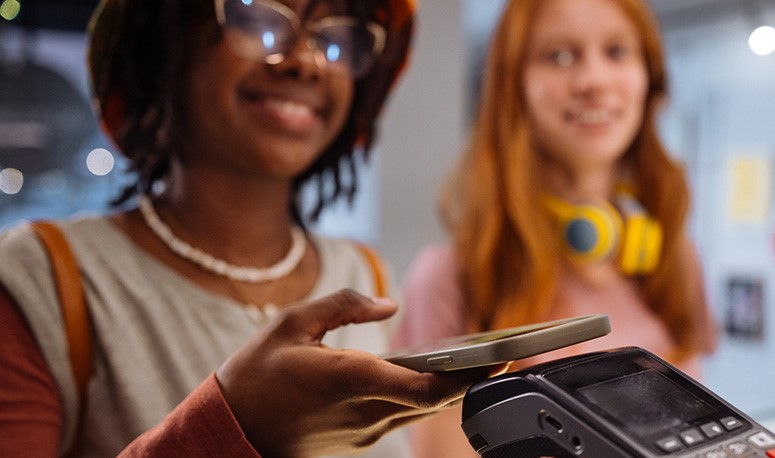 Two female teenagers making a purchase using mobile app on their phone.