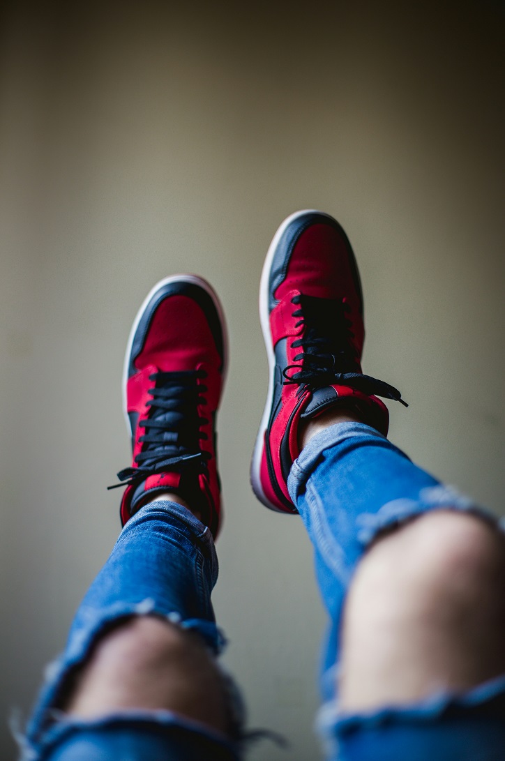 Person wearing ripped jeans and red and black sneakers