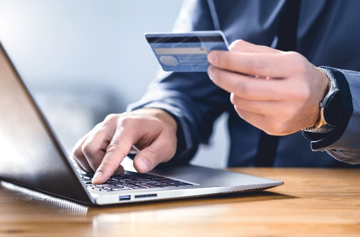 Man enters credit card information into a laptop.