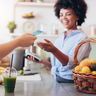 Woman at a juice bar takes credit card payment on handheld credit card machine