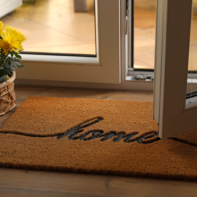 Slightly open glass door over a door mat that says home