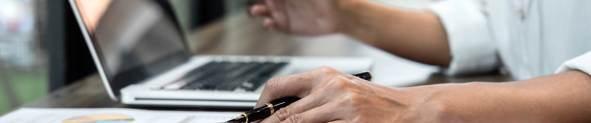 Man holding pen while pointing at laptop on desk