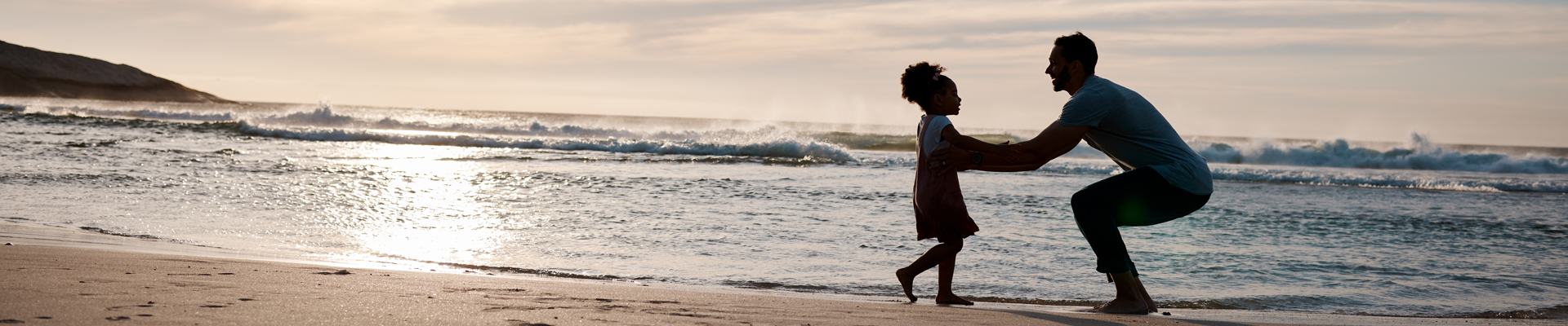 Father goes to pick up his daughter on the sand at the beach